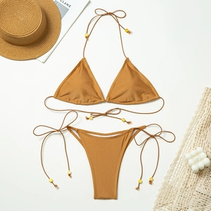 Flat lay of caramel bikini set with tie-sides and golden bead accents on white background
