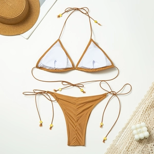 Close-up of dark khaki bikini set with gold bead details and summer beach accessories