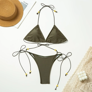 Deep olive green bikini set with neck ties and yellow beads on a vacation background