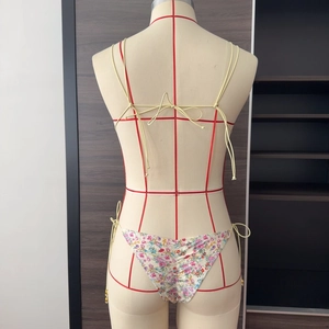Détail du bas de bikini floral avec design froncé au dos et liens jaunes