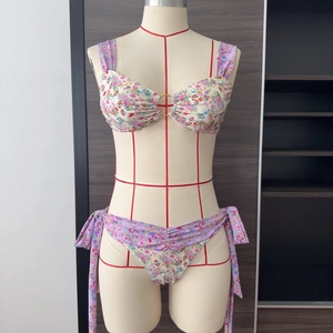 Détail du bikini à fleurs avec anneau métallique central et nœuds de ruban latéraux
