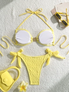 Yellow textured floral bikini set with halter top and metal buckle on soft white rug
