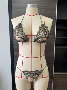 Détail d'un ensemble bikini beige avec broderie en dentelle florale noire et lacets