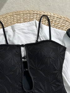 Gros plan d'un maillot de bain noir au crochet avec fines bretelles et boutons
