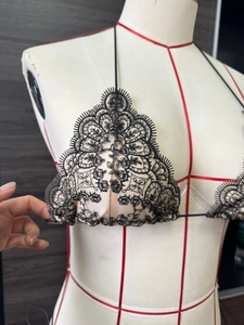 Détail de broderie en dentelle noire sur doublure chair sur un haut de bikini à fines brides