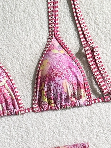 Pink floral triangle bikini top with red gingham straps on a plush background