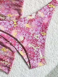 Three-piece floral bikini set in pink and purple tones on a white textured background