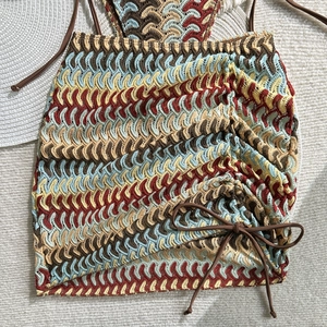 Detail of bohemian crochet mini skirt with colorful wave patterns and side drawstring bow
