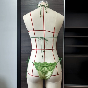 Détail du bas de bikini en dentelle verte avec broderie florale et breloques dorées