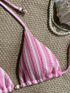 Pink and white striped crochet bikini top with bead details on a beach background