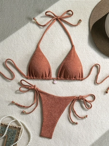 Detail of rust red waffle texture bikini set with shell charm and gold accents