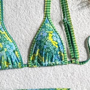 Detail of floral and gingham bikini top with adjustable straps on white towel