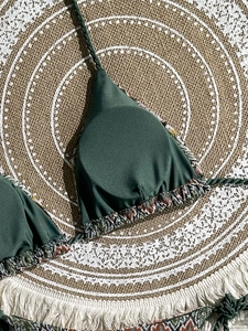 Dark green bikini top with ethnic print trim and braided neck straps on jute mat