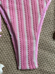 Pink and white striped crochet bikini bottom with pearl bead side ties on straw mat