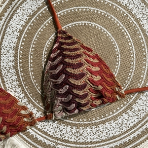 Close-up of bohemian crochet knit bikini top with intricate wave textures in warm earthy tones