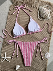 Pink and white striped crochet bikini set with lace-up details on a beach themed background