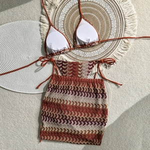 Detail view of 3-piece halter bikini and crochet wave pattern skirt on a beach mat