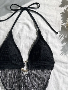 Dettaglio del top bikini nero con anello dorato e texture in rete trasparente chic