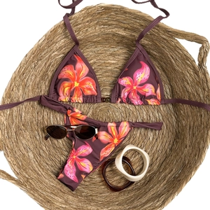 Close-up of dark floral bikini with orange flowers, bead accents, and beach accessories