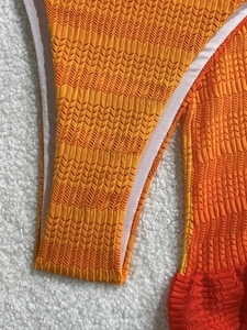 Macro view of textured orange mesh bikini fabric with fine wavy knit and white lining