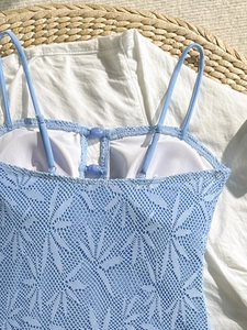 Détail de la dentelle bleu clair avec motif floral ajouré et boutons décoratifs