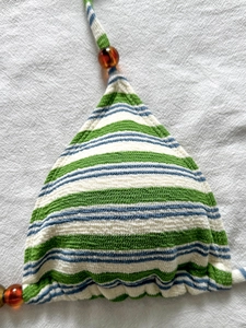 Dettaglio del top bikini a righe con texture a maglia e accenti di perle ambrate