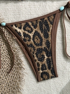 Detail of leopard print bikini bottom with black sequins and turquoise bead ties