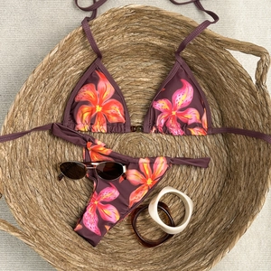 Flat lay of floral bikini set in a woven basket with summer sunglasses and bracelets