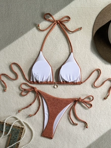 Flat lay of an orange bikini set with textured fabric, side ties, and golden bead details