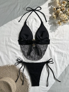 Dettaglio del bikini nero con inserti in rete e anello in metallo dorato lucido