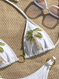 Bikini blanc avec broderie de palmier en perles et anneaux en métal sur tapis de plage