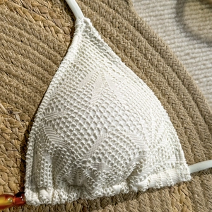 Détail de haut de bikini en crochet blanc avec motifs bohèmes et perles ambrées élégantes