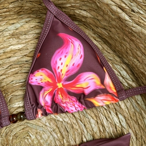 Detail of floral bikini top with amber beads on woven straw background