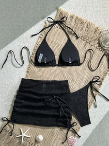 Dettaglio del bikini nero a tre pezzi con gonna in pizzo ed etichetta della taglia S