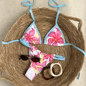 Detailed close-up of floral bikini set in woven basket with stylish vacation accessories