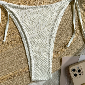 Détail du bas de bikini au crochet blanc avec dentelle bohème et liens latéraux