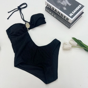 Chic black one-piece bikini with ribbed texture, halter neck, and gold B-shaped metal buckle