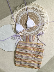 Detail view of purple crochet bikini set with wave pattern and halter ties on beige rug
