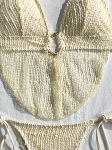 Dettaglio bikini all'uncinetto crema con anello dorato e trama a maglia fine