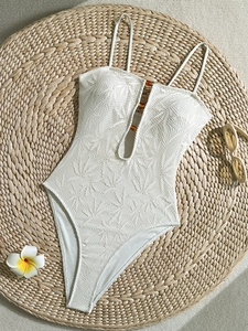 Détail d'un maillot de bain blanc au crochet avec dentelle tropicale et perles ambrées
