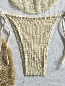 Dettaglio dello slip bikini beige in maglia crochet con lacci laterali e tessuto a rete