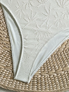 Gros plan sur la dentelle florale au crochet d'un maillot de bain blanc sur une natte