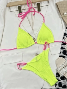 Detail of neon yellow ribbed bikini with pink straps and metal ring on white blazer