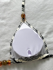 Dettaglio del top bikini a righe con perline ambrate e imbottitura rimovibile