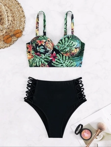 Flat lay of tropical floral bikini top with black high-waisted lace-up side swim bottoms