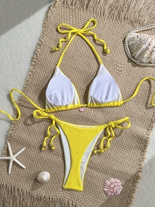 Detailed macro view of yellow ribbed bikini fabric, S size label, and gold bead ties