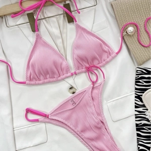 Pink ribbed bikini set with halter triangle top and high-cut bottom on beach accessories