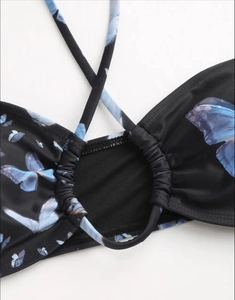Detail of black halter bikini top with light blue butterfly print on glossy stretch fabric