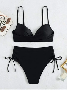 Flat lay of black high waist bikini set with pleated details and side tie bows on marble