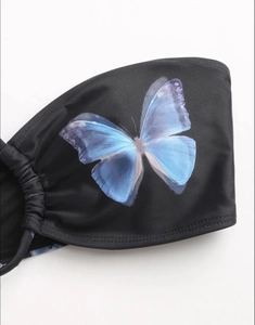Detail of black bikini top with blue butterfly print and side drawstring ruching texture